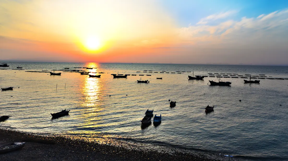 Golden sunset over the sea with silhouetted boats near the shore