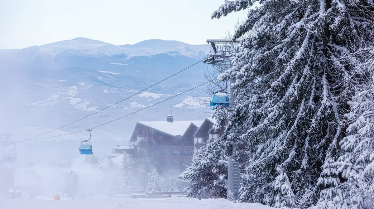 Kabina gondole që ngjiten mbi pishat me borë drejt majave në Bansko, Bullgari