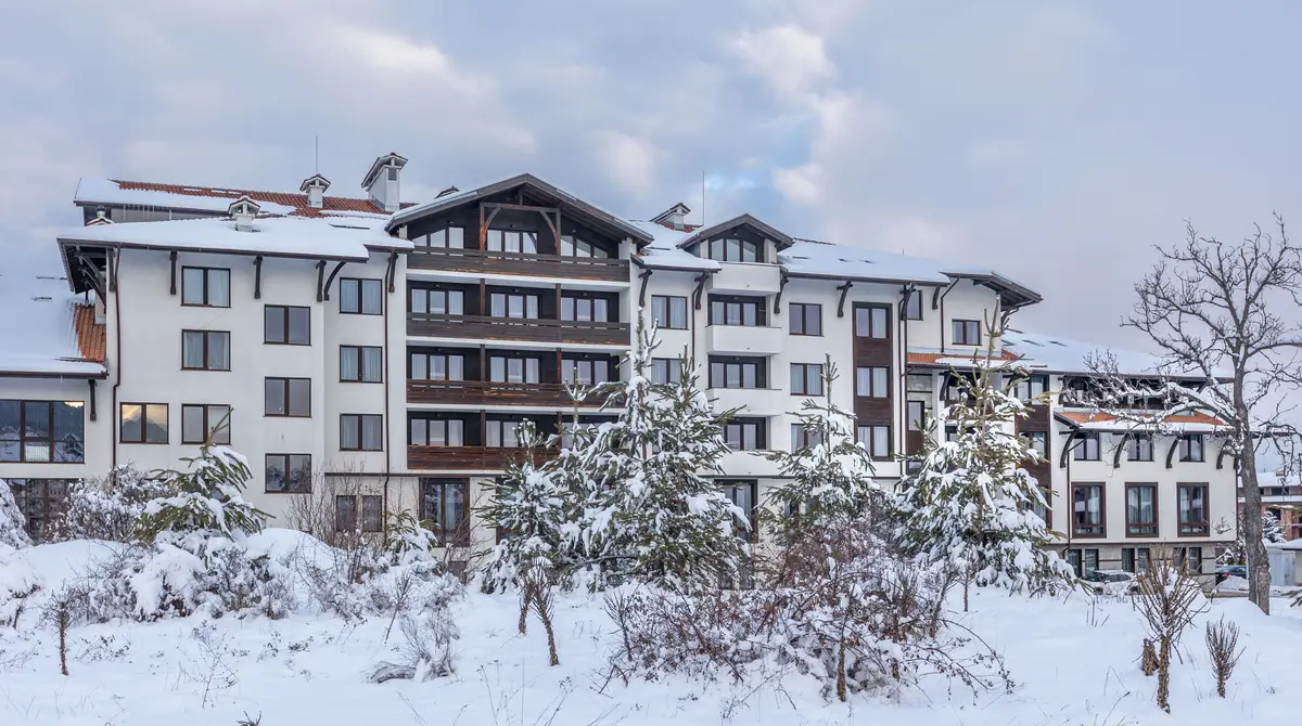 Hotel në stil vile alpine me ballkone druri, i mbuluar me borë mes pishave në Bansko, Bullgari