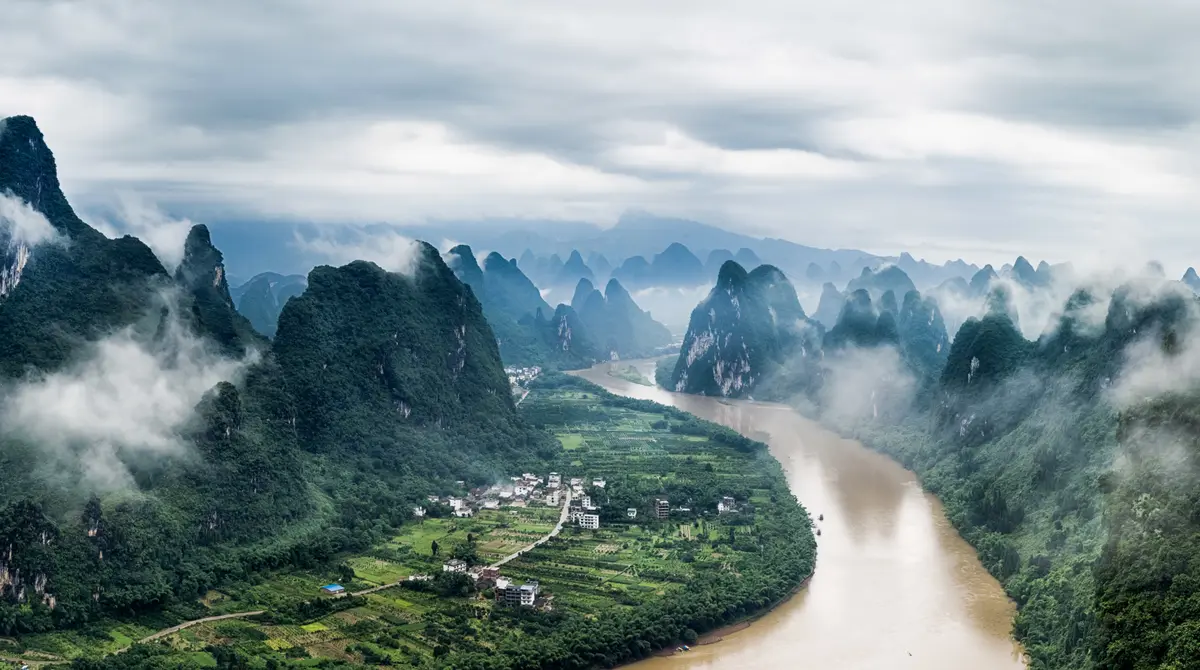 Trap bambuje në lumin Li me mjegull mes majave karstike të gjelbra afër Yangshuo, Guilin