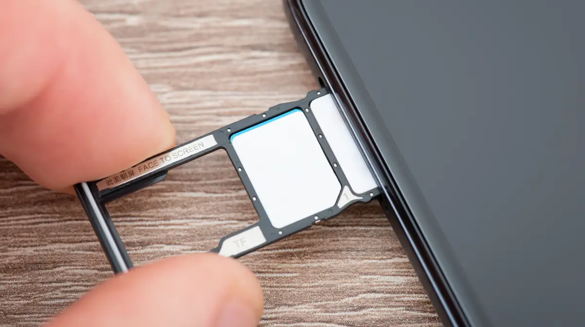 Duar që mbajnë një kartë SIM fizike dhe gjilpërën e sirtarit mbi një telefon