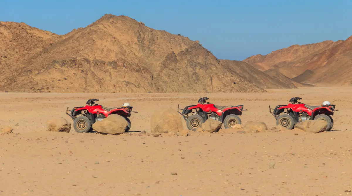 Quad bikes riding over desert dunes at sunset near Hurghada, Egypt