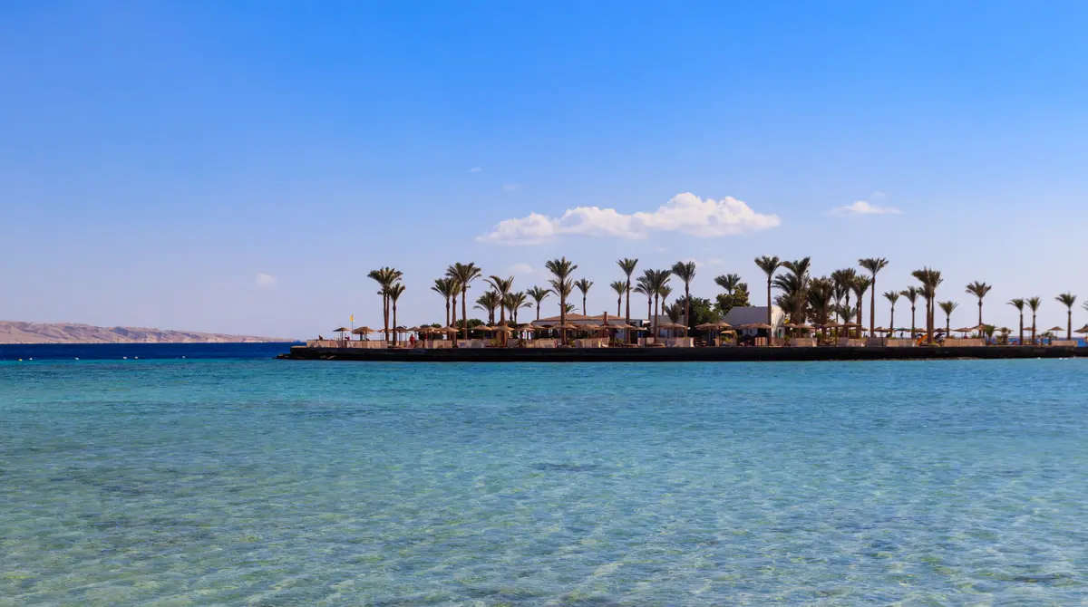 Sandy Red Sea beach with turquoise water and palm umbrellas in Hurghada, Egypt