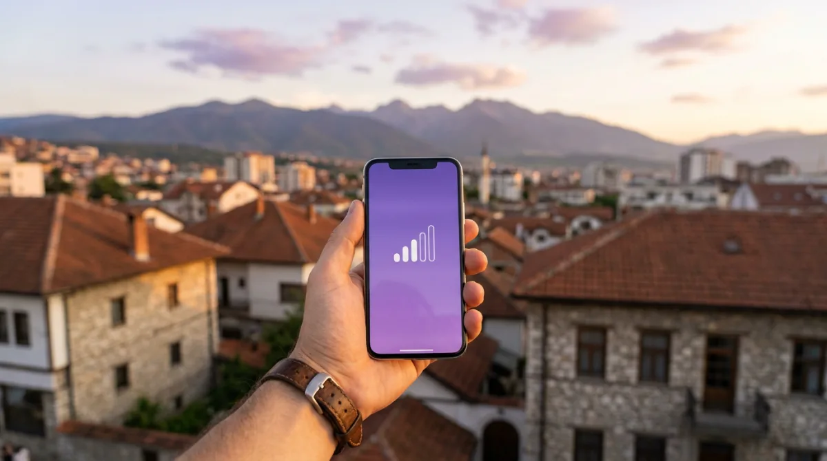 Udhëtar duke kontrolluar sinjalin në telefon mbi çatitë e Prishtinës