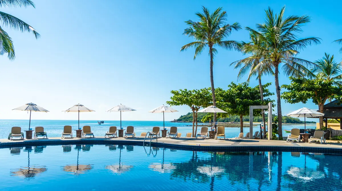 Resort swimming pool with palm trees next to the beach in Punta Cana, Dominican Republic