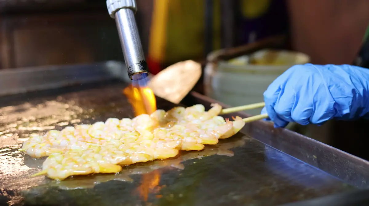 Busy Thai street food market stall with wok cooking and fresh dishes at night