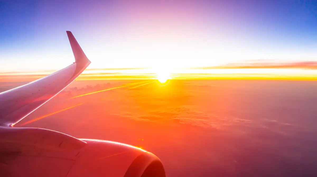 Krahu i avionit mbi re në perëndim të diellit